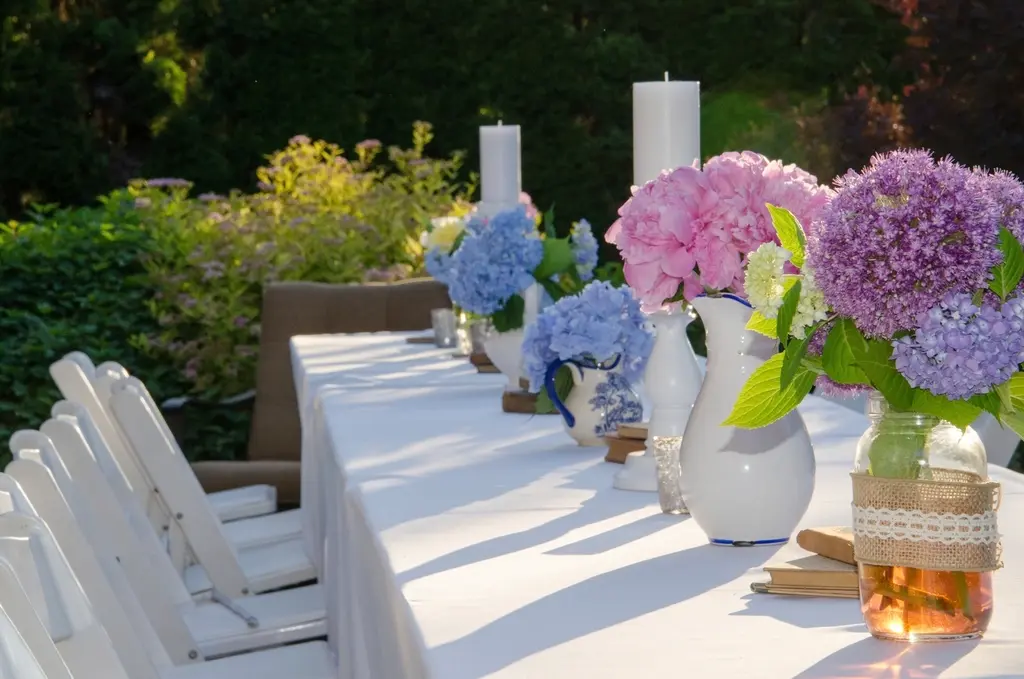 Mesa larga al aire libre puesta para una comida de celebración, con la luz de la tarde