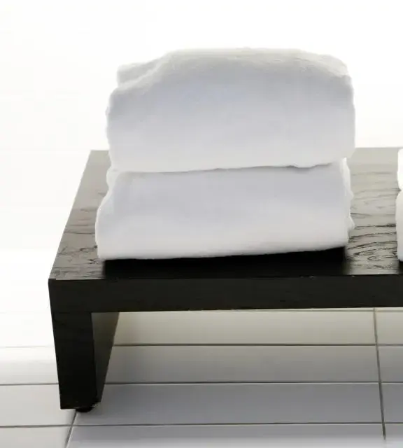 Toallas blancas dobladas sobre un banco de madera oscura