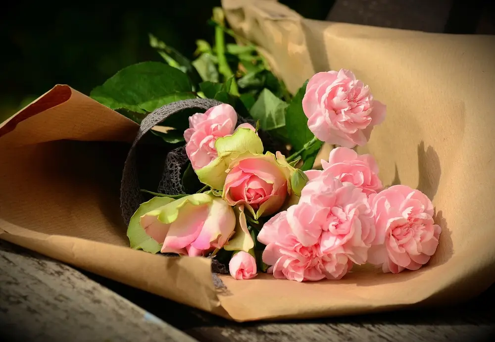 Ramo de claveles rosas envuelto en papel de estraza.