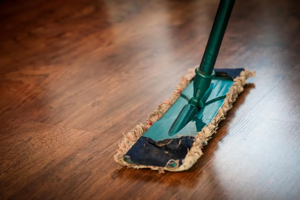 Mopa verde pasando sobre un suelo de madera brillante