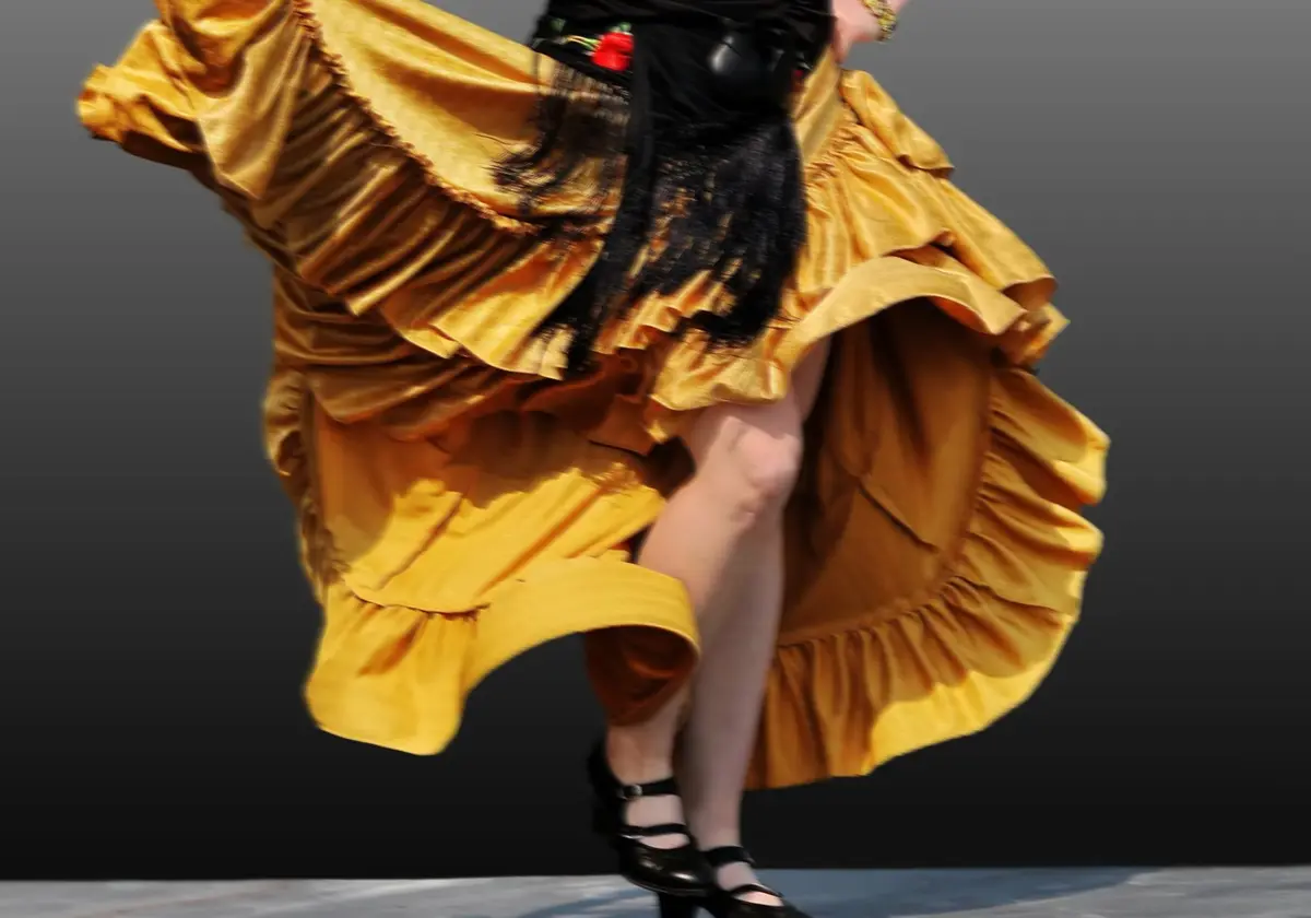 Falda amarilla de flamenco girando y zapatos negros de tacón marcando el paso