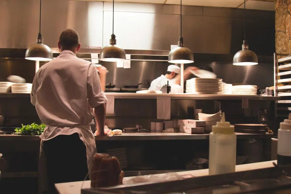 Un cocinero de espaldas en la cocina del restaurante, bajo las lámparas