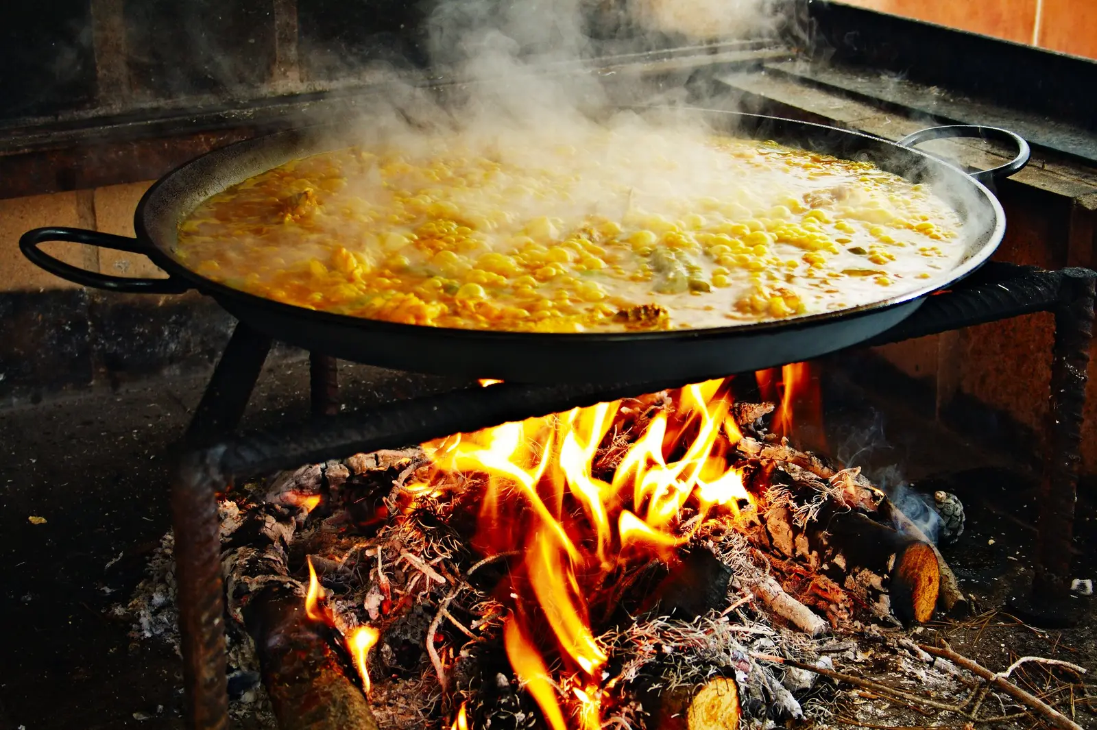 Paella cociéndose a la leña, con el caldo hirviendo