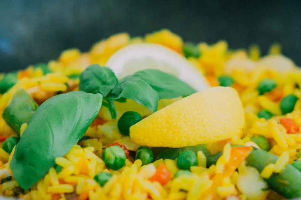 Detalle de un arroz con verduras, guisantes y limón