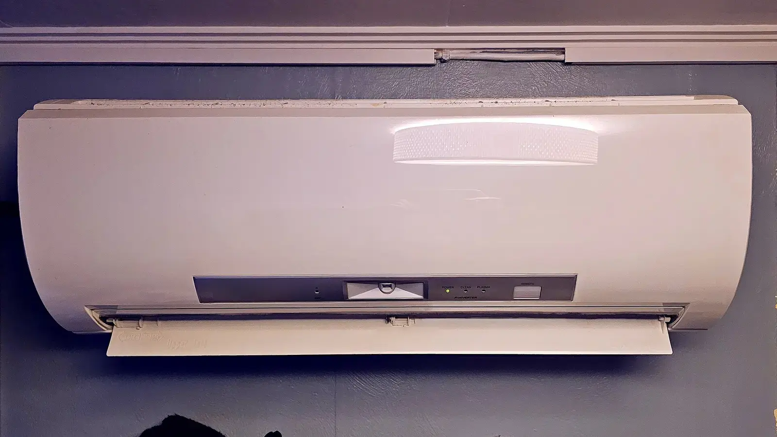 Unidad interior de aire acondicionado blanca, colgada en lo alto de una pared