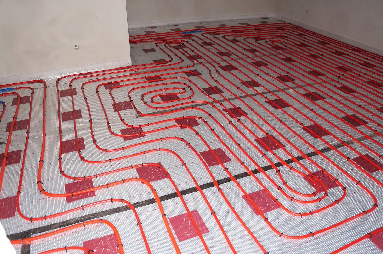 Suelo radiante recién montado, con los tubos rojos en espiral sobre las placas de aislante
