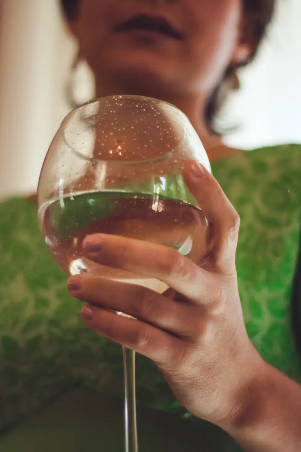 Una invitada sostiene una copa de vino blanco