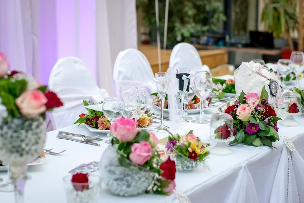 Mesa del banquete con mantel blanco y centros de rosas