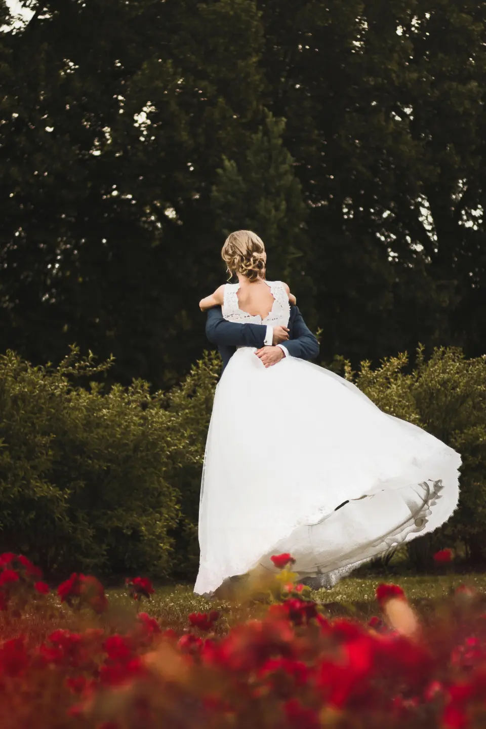 La novia da una vuelta y el vestido se abre sobre un parterre de flores rojas