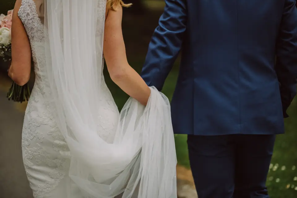 Los novios de espaldas; él le sujeta la cola del vestido
