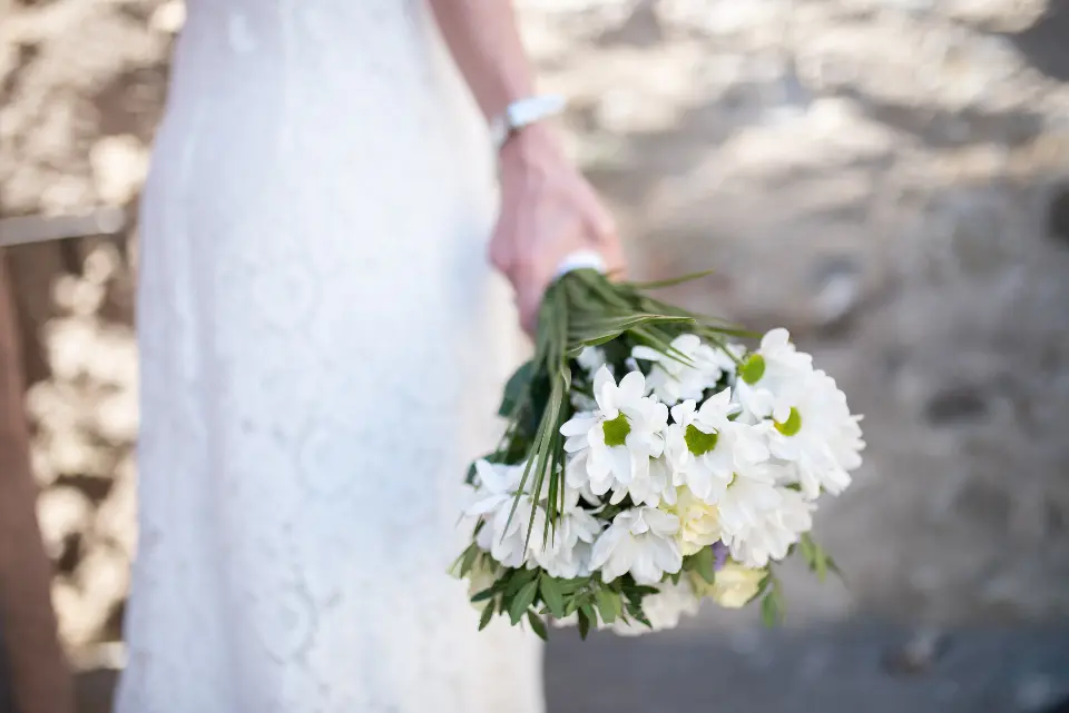 La novia baja la mano con un ramo de margaritas