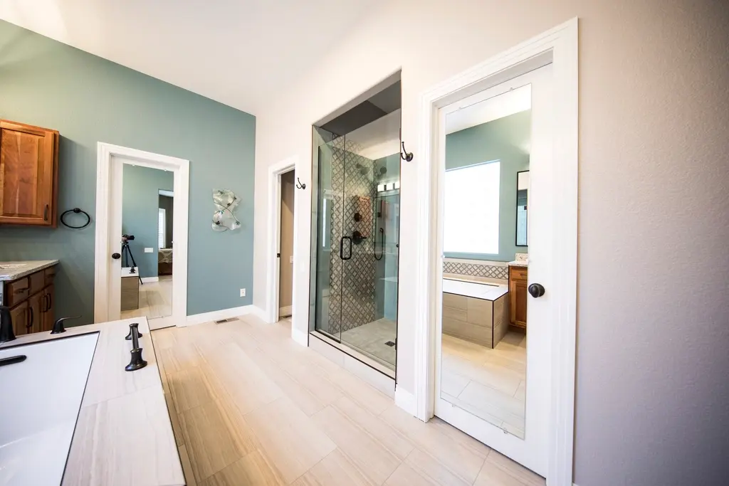 Baño amplio con paredes azul grisáceo, ducha acristalada y suelo de madera clara