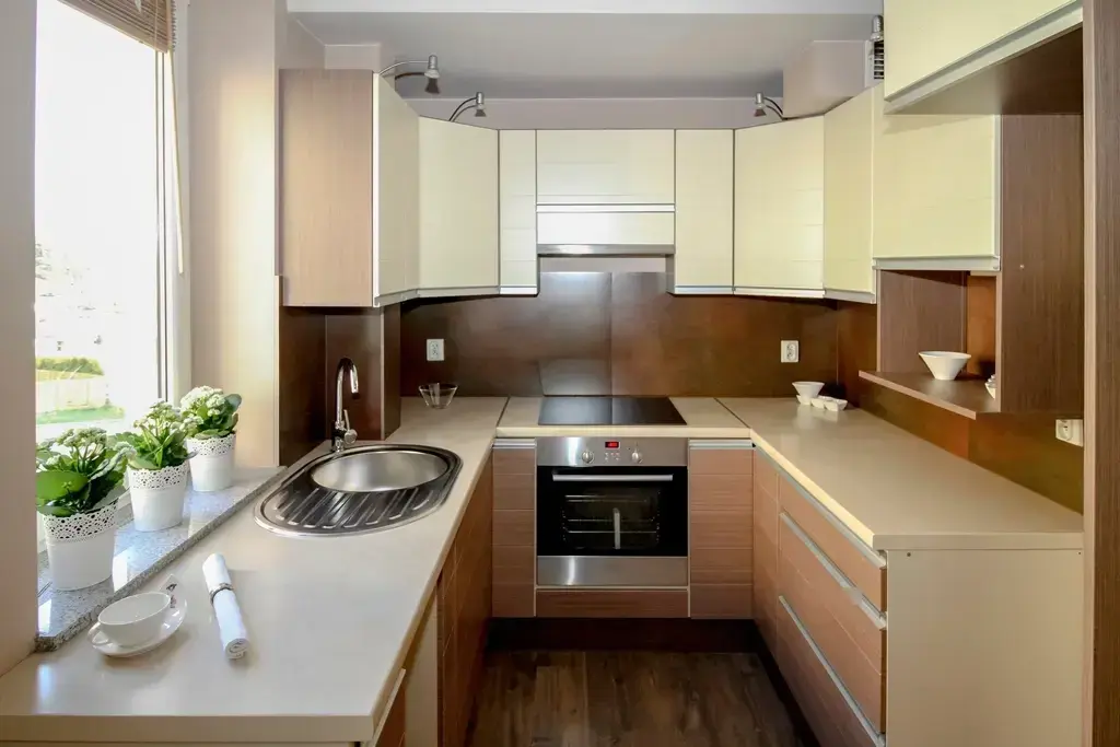 Cocina pequeña en U con muebles de madera y blancos y ventana con plantas