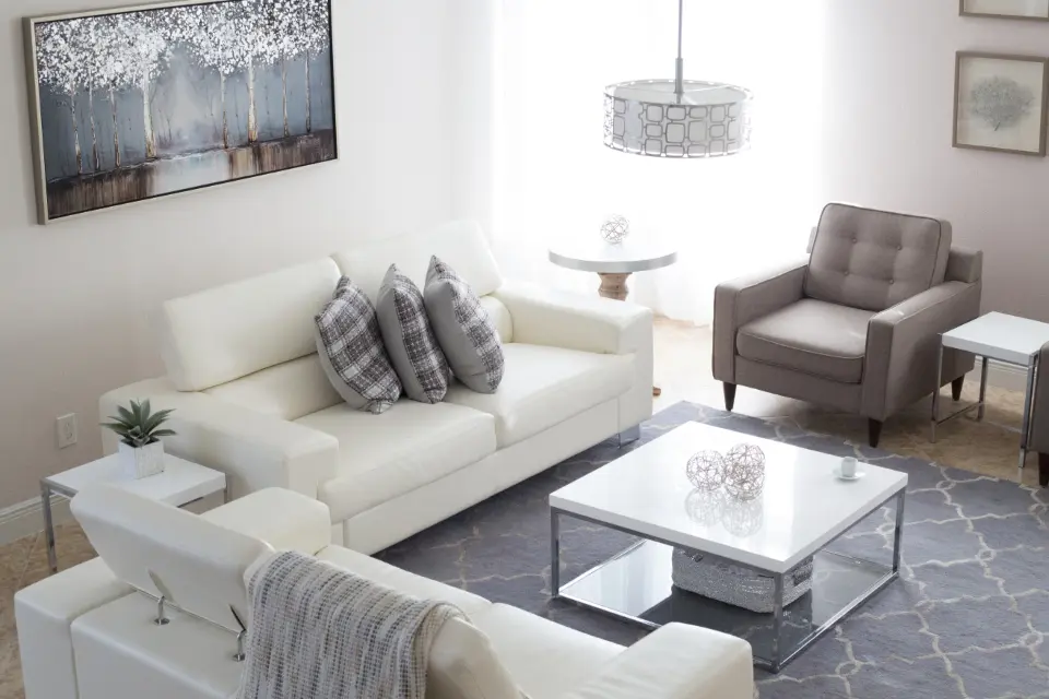 Salón con paredes blancas, sofás claros y alfombra gris