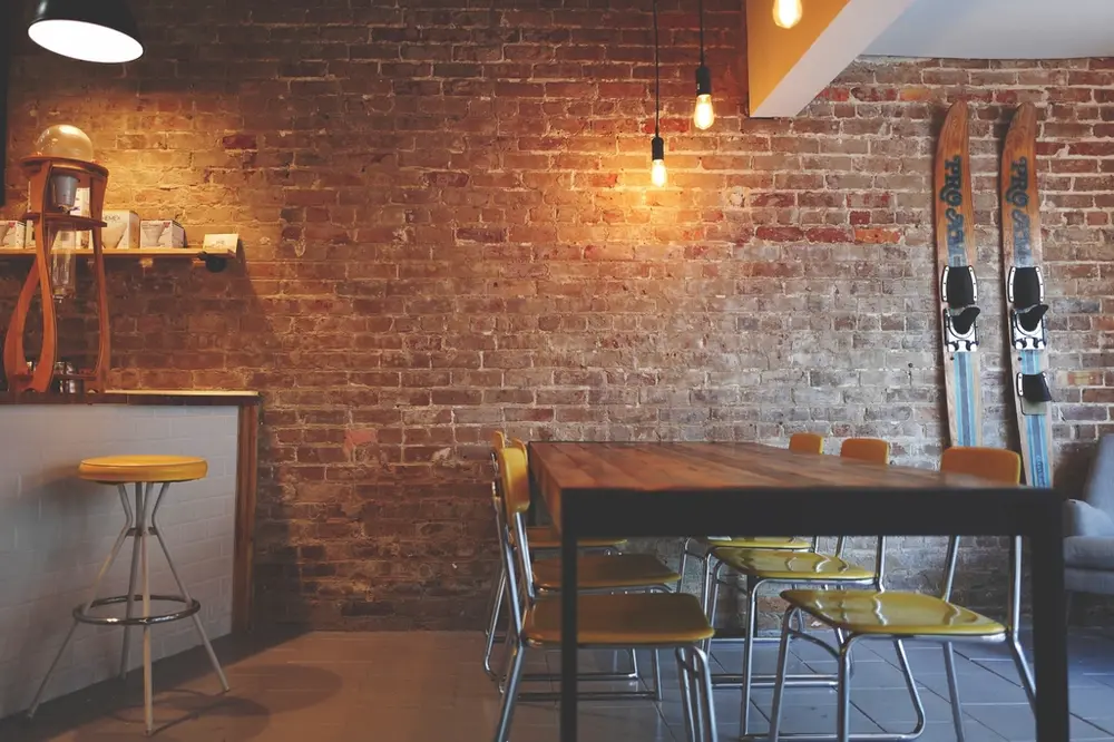 La sala con la mesa larga y la pared de ladrillo