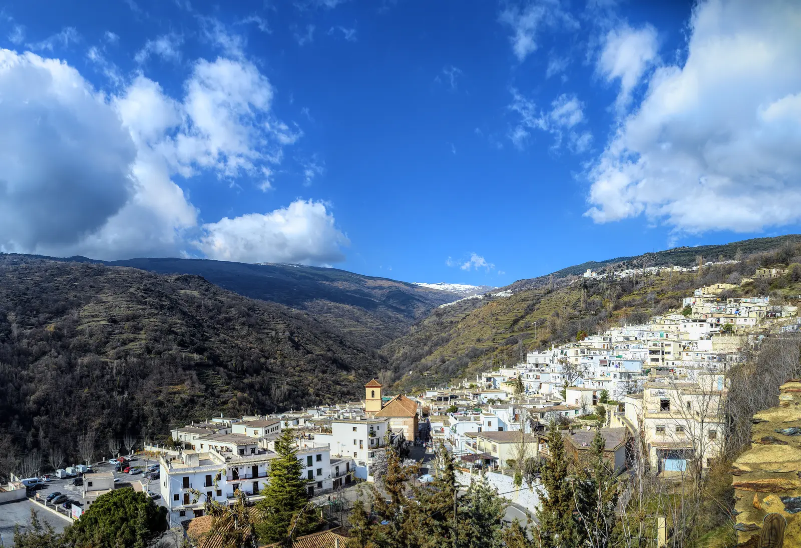 Pueblos blancos de la Alpujarra en la ladera, con bancales y la sierra detrás.