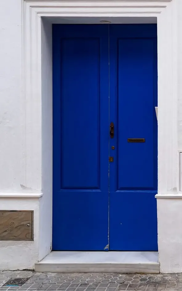 Puerta azul añil de El Horno en la pared encalada.