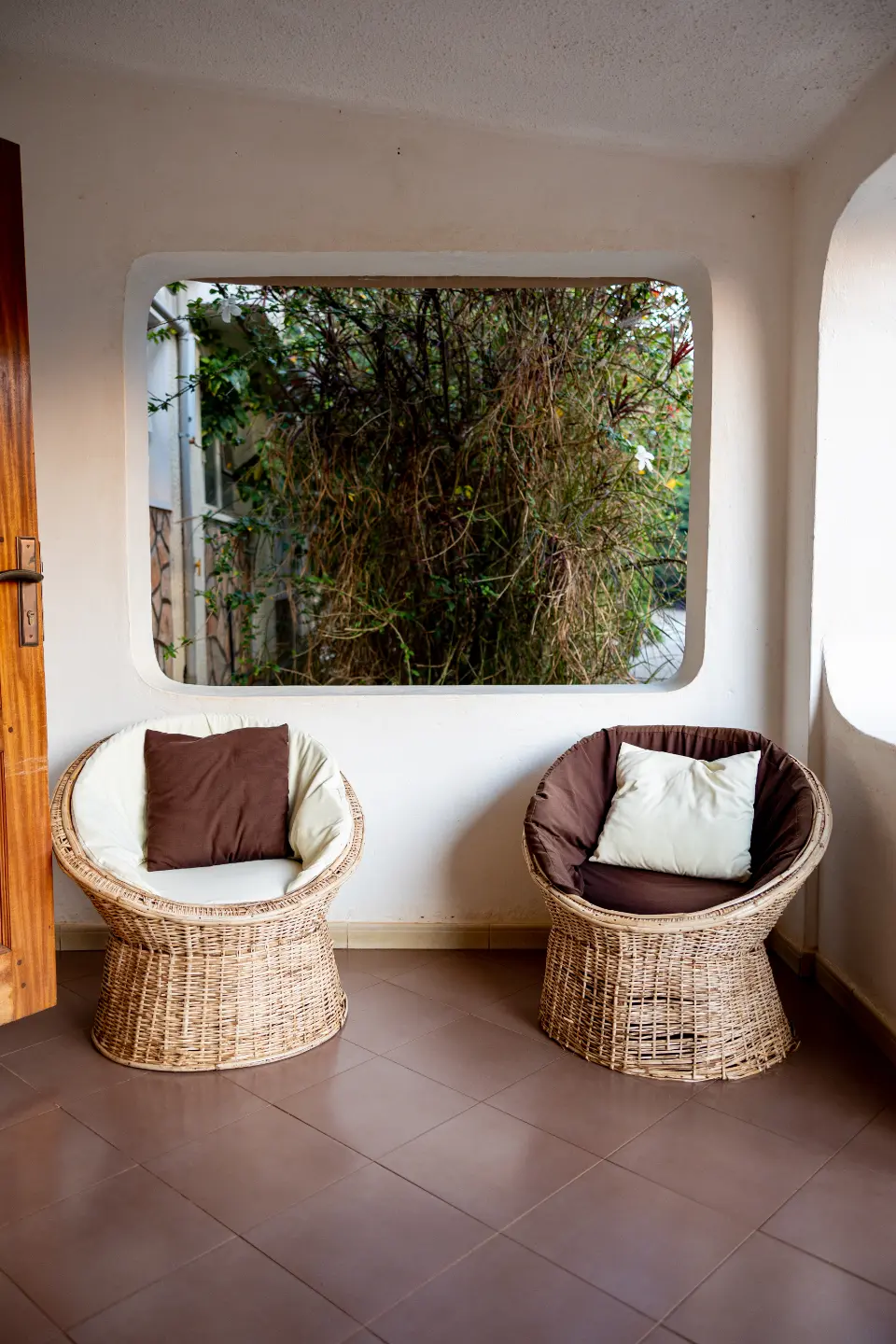 Galería de La Alberca con dos butacas de mimbre frente a una ventana abierta al jardín.