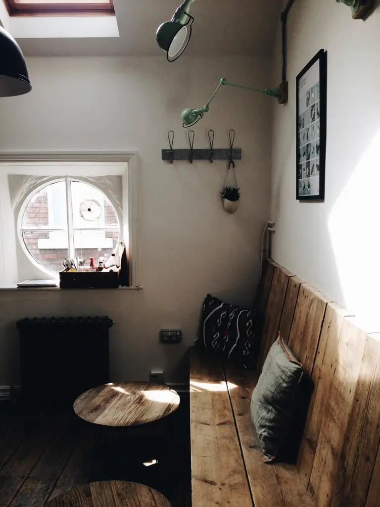 Rincón de La Era con banco de madera, ventana redonda y mesa baja al sol de la mañana.
