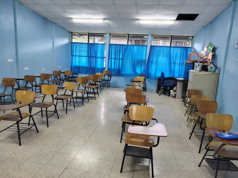 Aula vacía con pupitres de madera y ventanas grandes