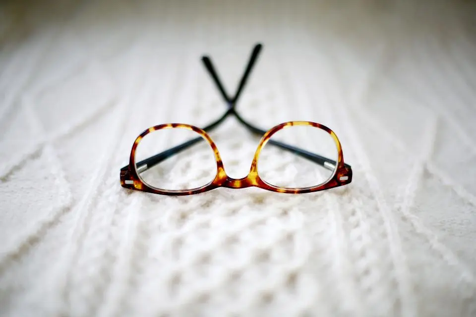 Gafas de pasta de carey apoyadas sobre un jersey de punto blanco
