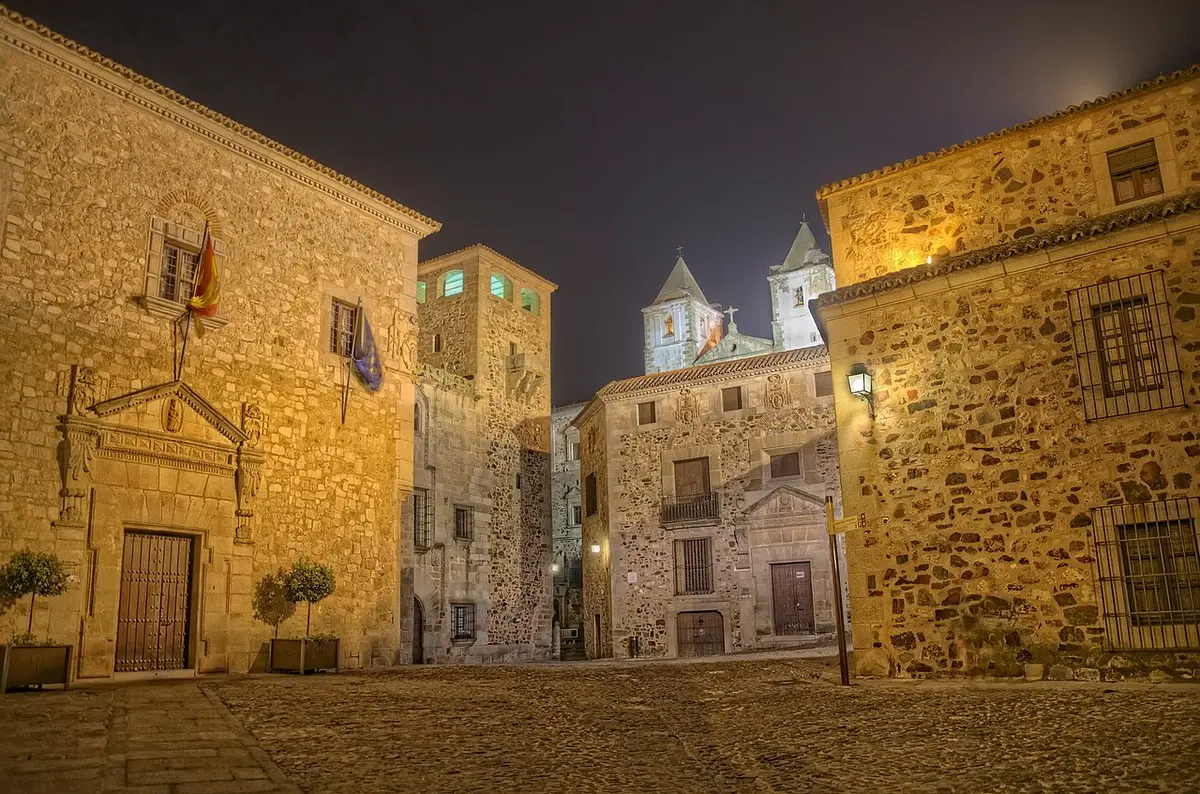 Plaza de piedra del casco antiguo de Cáceres de noche, iluminada por las farolas y sin nadie.
