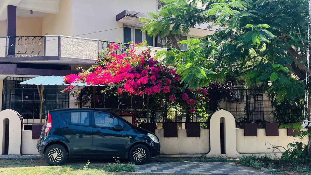 Coche utilitario azul oscuro aparcado frente a una casa con buganvillas