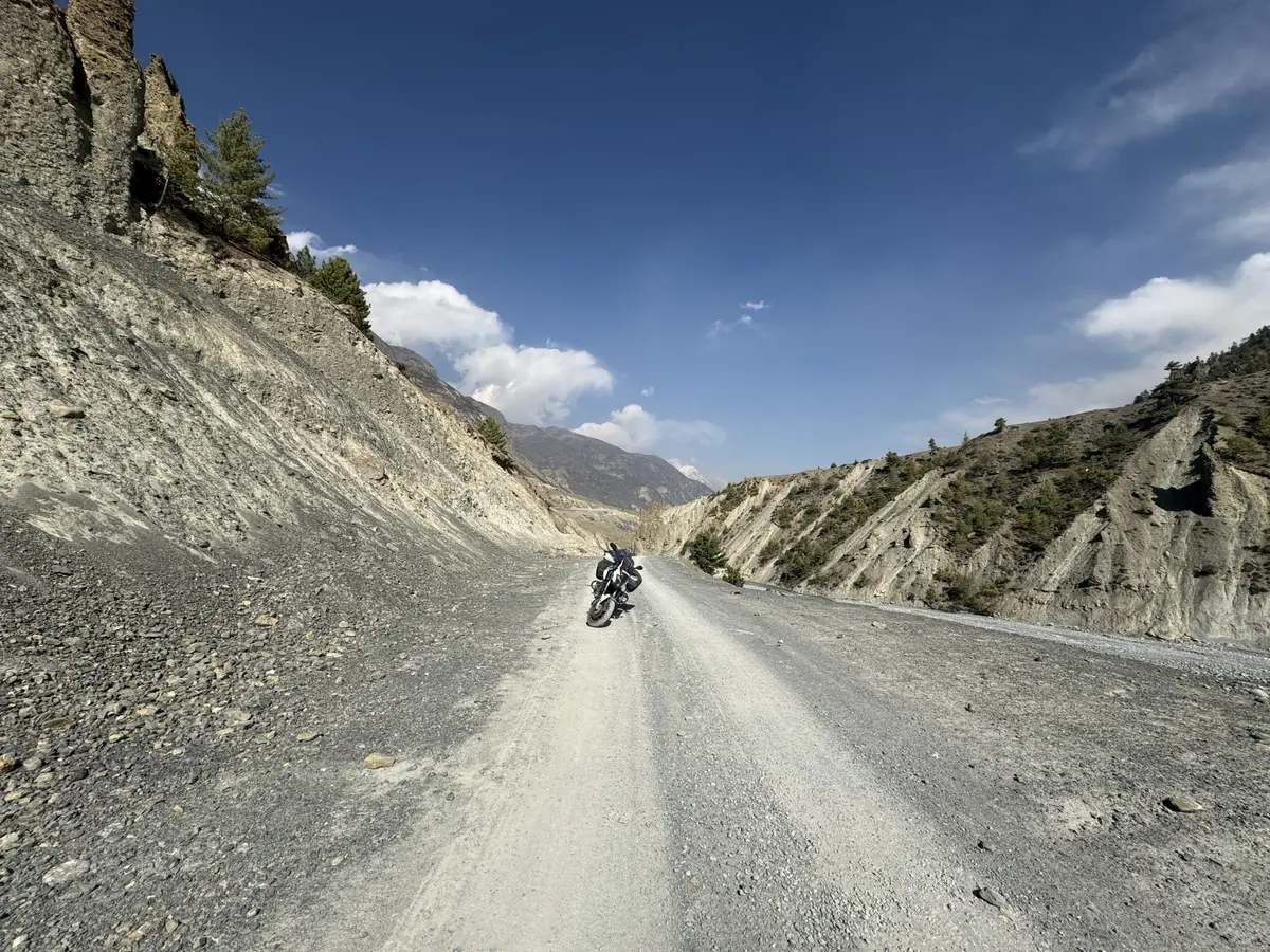 Moto en una pista de montaña entre laderas de roca, vista de lejos