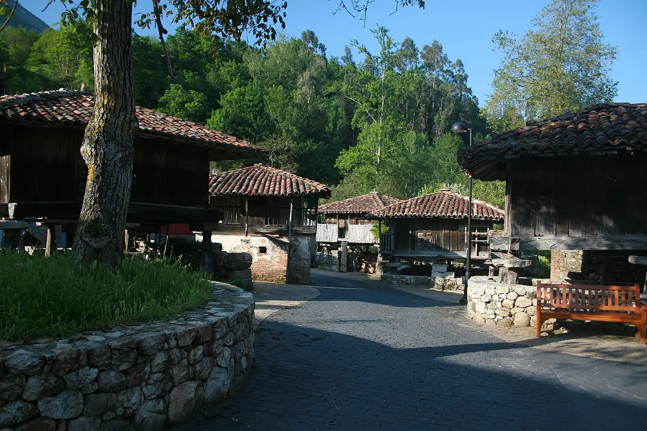 Camino de una aldea con varios hórreos de madera sobre pilares y muros de piedra