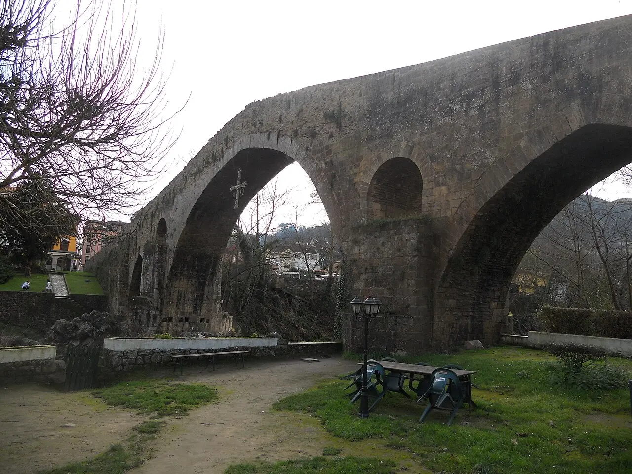 Puente de piedra de arco alto con una cruz colgando bajo el arco