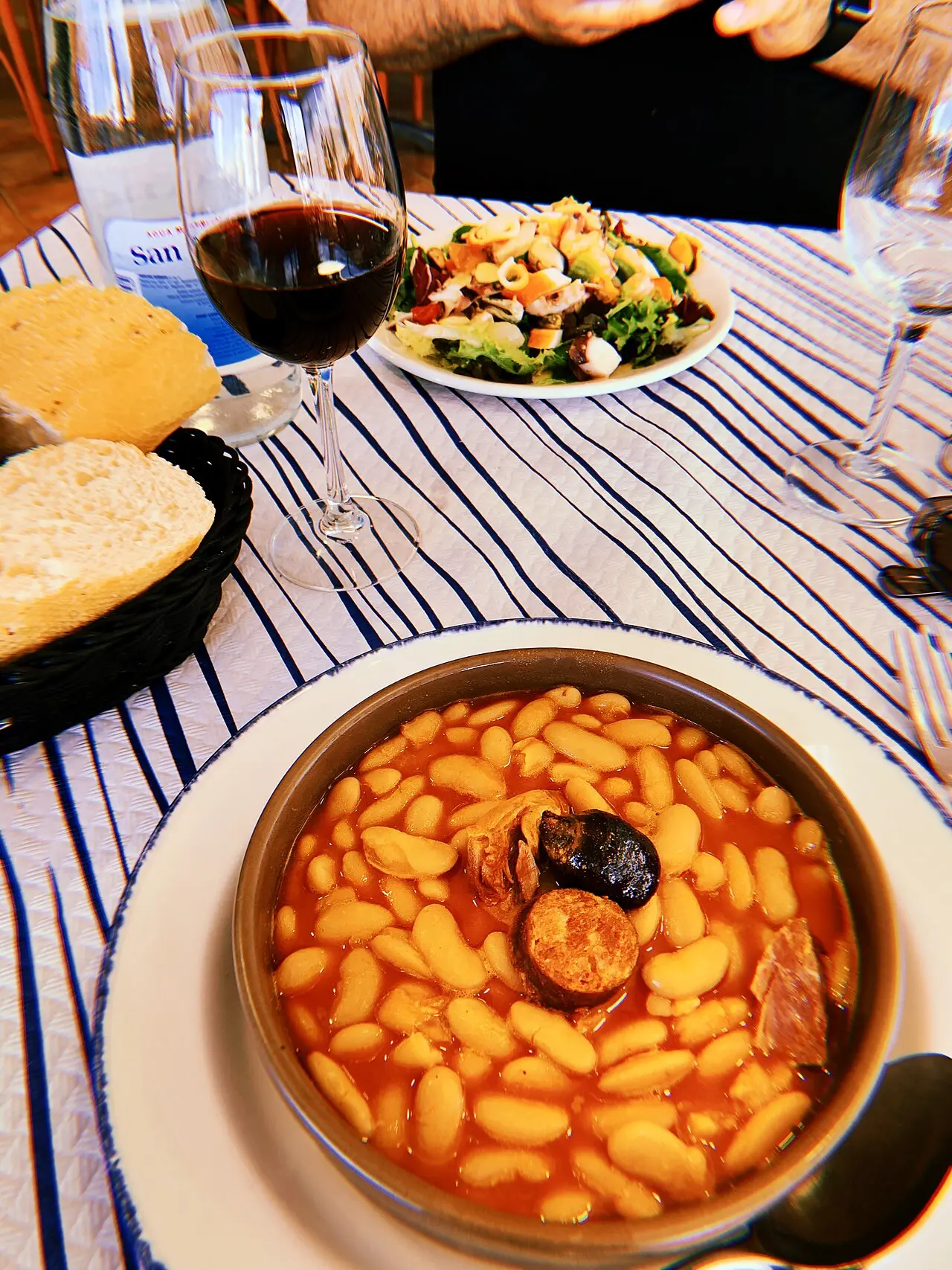 Cazuela de fabada asturiana con chorizo y morcilla sobre un mantel de rayas