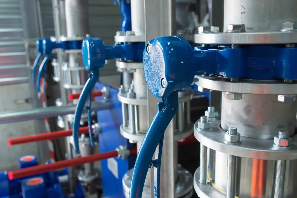 Válvulas azules y tuberías de acero inoxidable en una sala de proceso