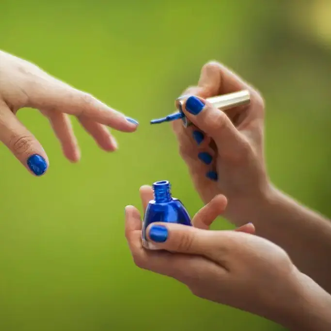 Pintando de azul eléctrico las uñas de una clienta
